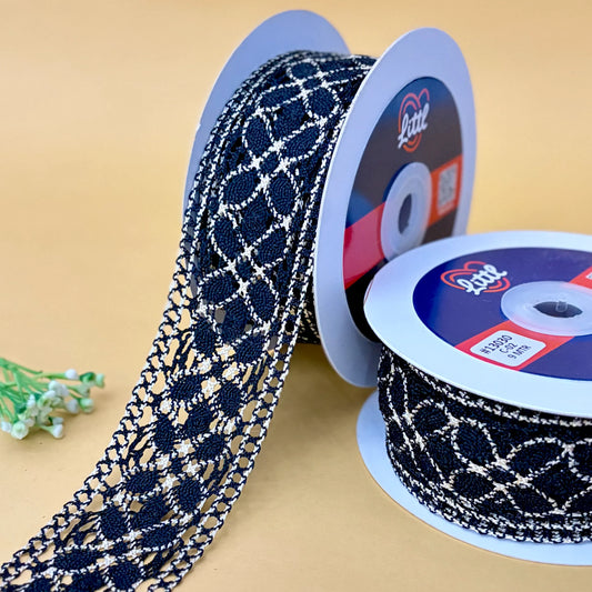 Two spools of black and white patterned lace ribbon with a visible brand logo on a beige background.