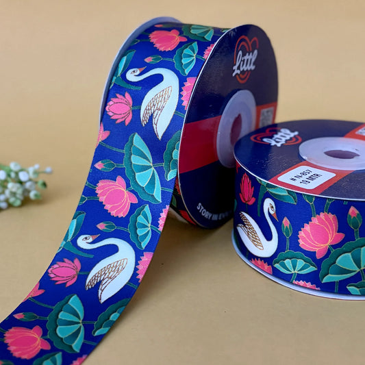 Two spools of ribbon with floral and swan design on a beige background