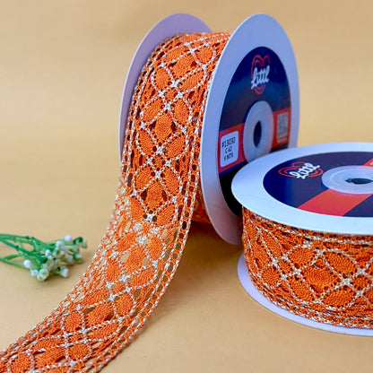 Orange lace ribbon on spools with a visible brand label against a beige background