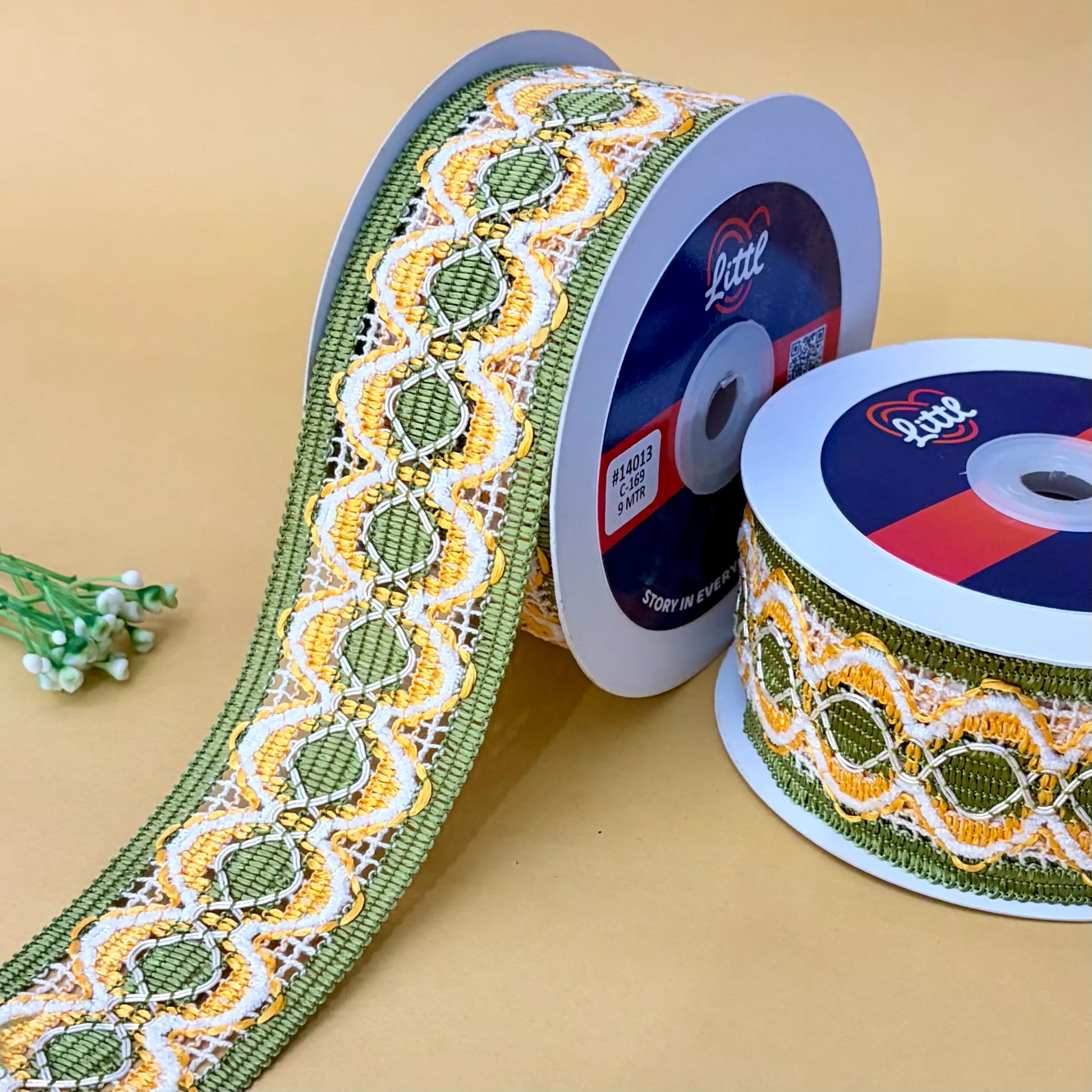 Two spools of decorative ribbon with a pattern on a beige background