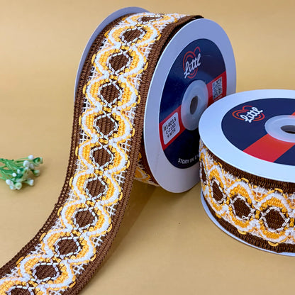 Two spools of decorative ribbon with a pattern on a beige background