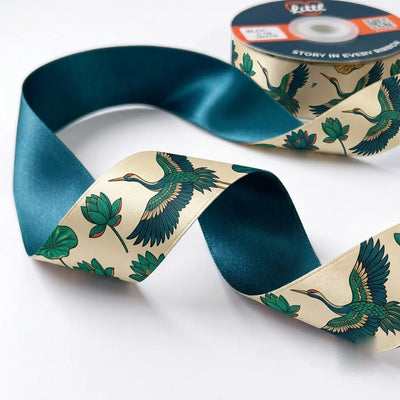 Close-up of Crane & Lotus ribbon: green cranes in flight and lotus leaves printed on cream satin