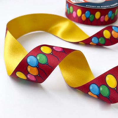 Close-up of Balloon Party ribbon: bunches of colourful balloons printed on maroon satin