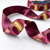 Close-up of Ginkgo Rose ribbon: pink and gold ginkgo leaves printed on magenta satin