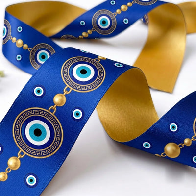 Close-up of Nazar Medallion ribbon: evil eye medallions in Greek key rings with gold bead chains printed on royal blue satin, antique gold back