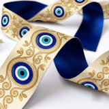 Close-up of Nazar Filigree ribbon: evil eyes in gold filigree scrolls printed on cream satin, navy blue back