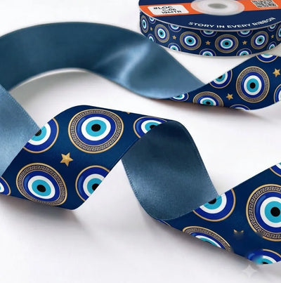 Close-up of Nazar Night ribbon: evil eyes and gold stars printed on navy blue satin, slate blue back