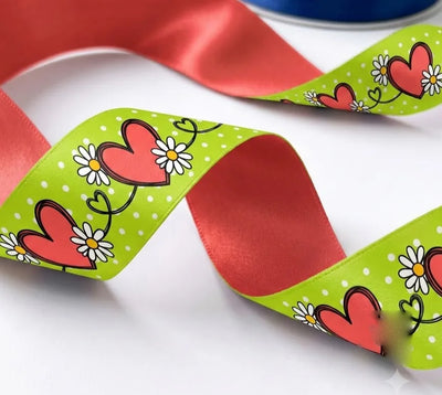 Close-up of Heart Vine ribbon: red hearts and white daisies on a vine printed on lime green satin, coral red back